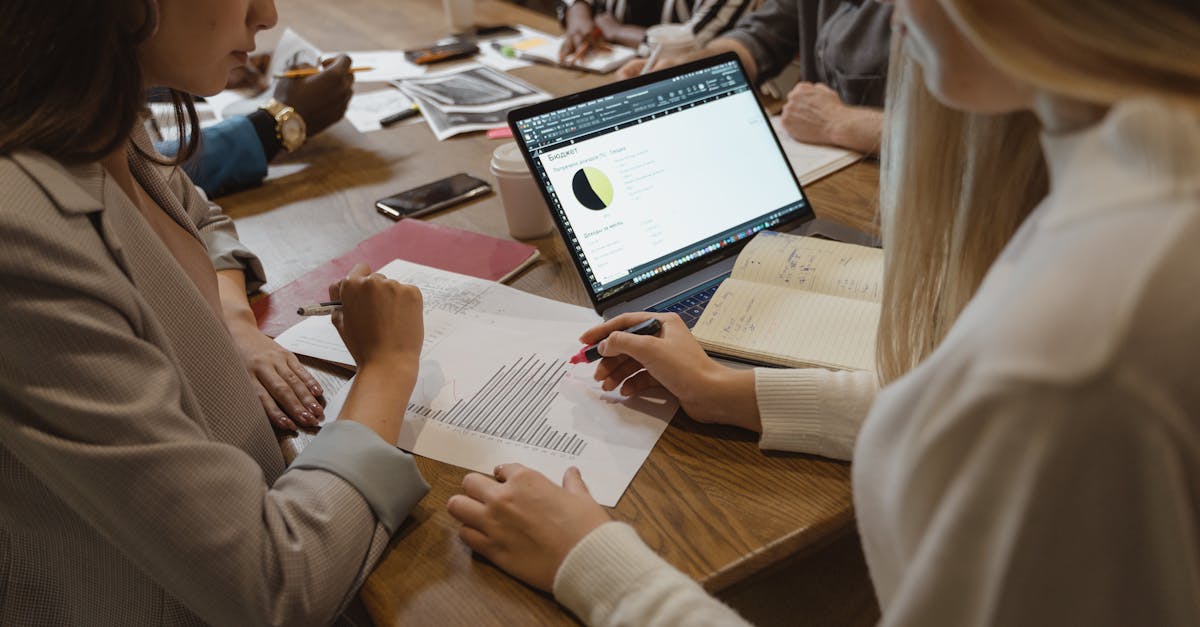 A diverse team collaborates on business strategy around a table with laptops and documents.