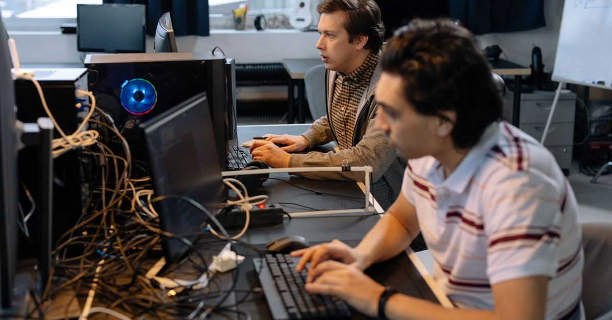 Male programmers working on computers in a modern office setting, showcasing teamwork and technology.