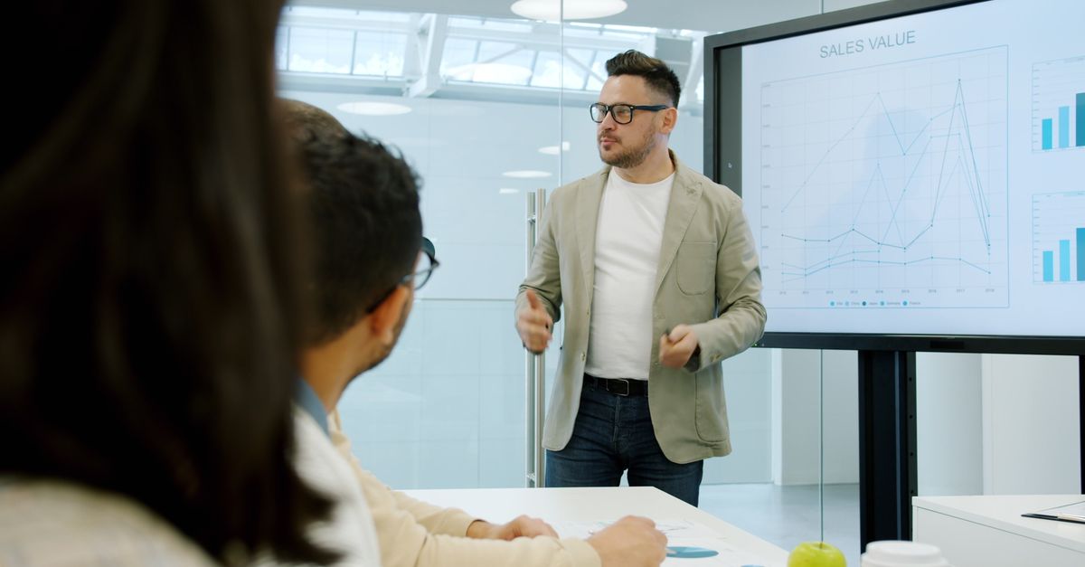 Business presentation with charts discussing sales growth in conference room.