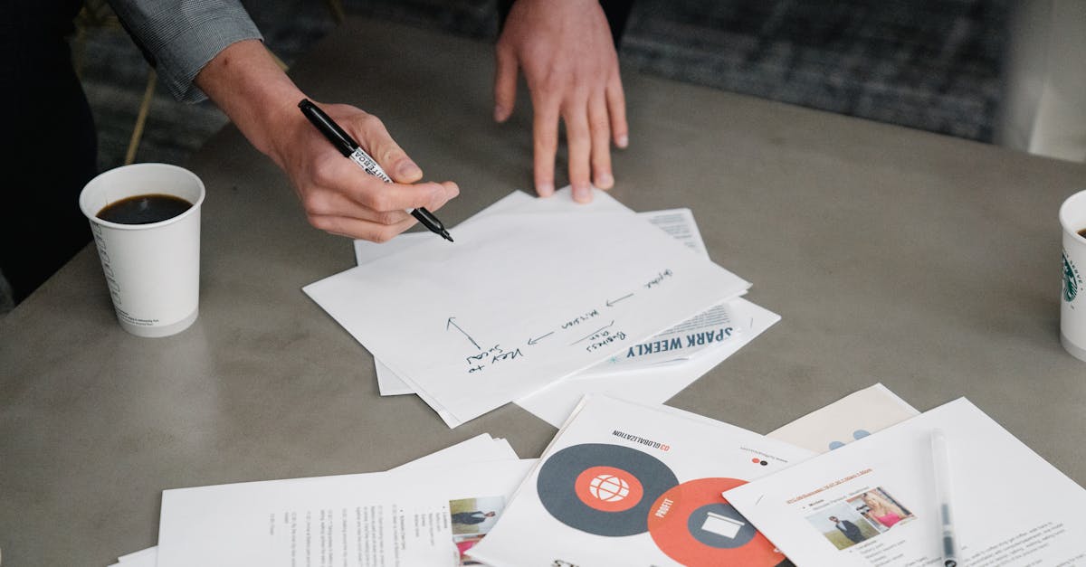 Two people collaborate during a business meeting, writing notes on papers with coffee cups nearby.