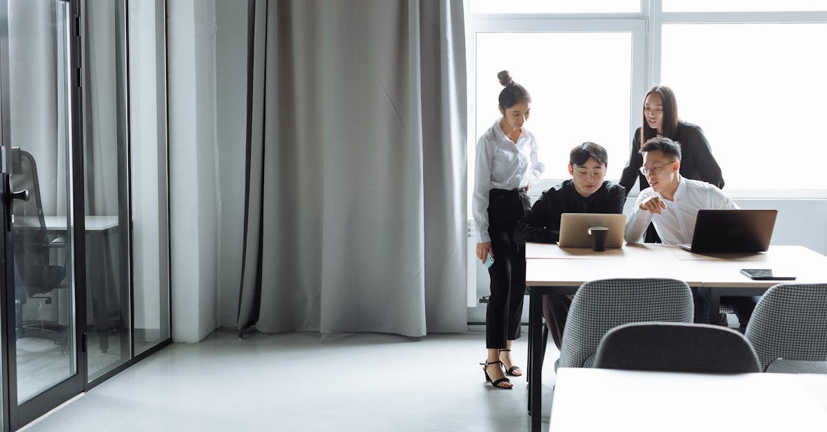 A diverse office team collaborating on laptops during daylight hours.