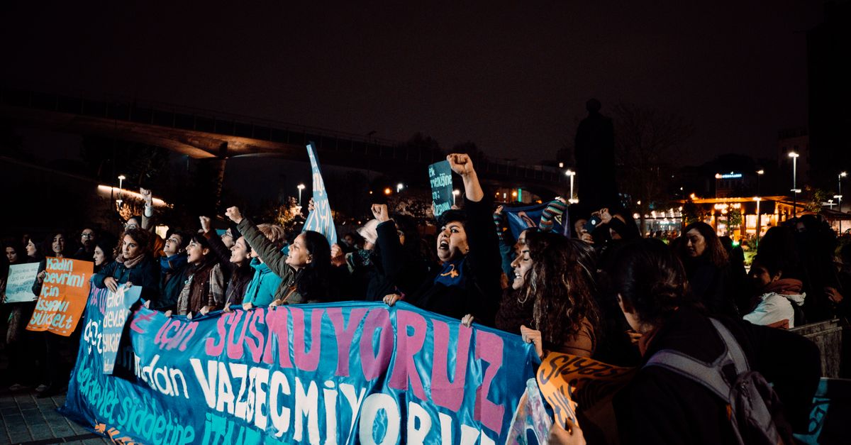 A group of protesters holding banners during a nighttime protest in İstanbul, Türkiye.
