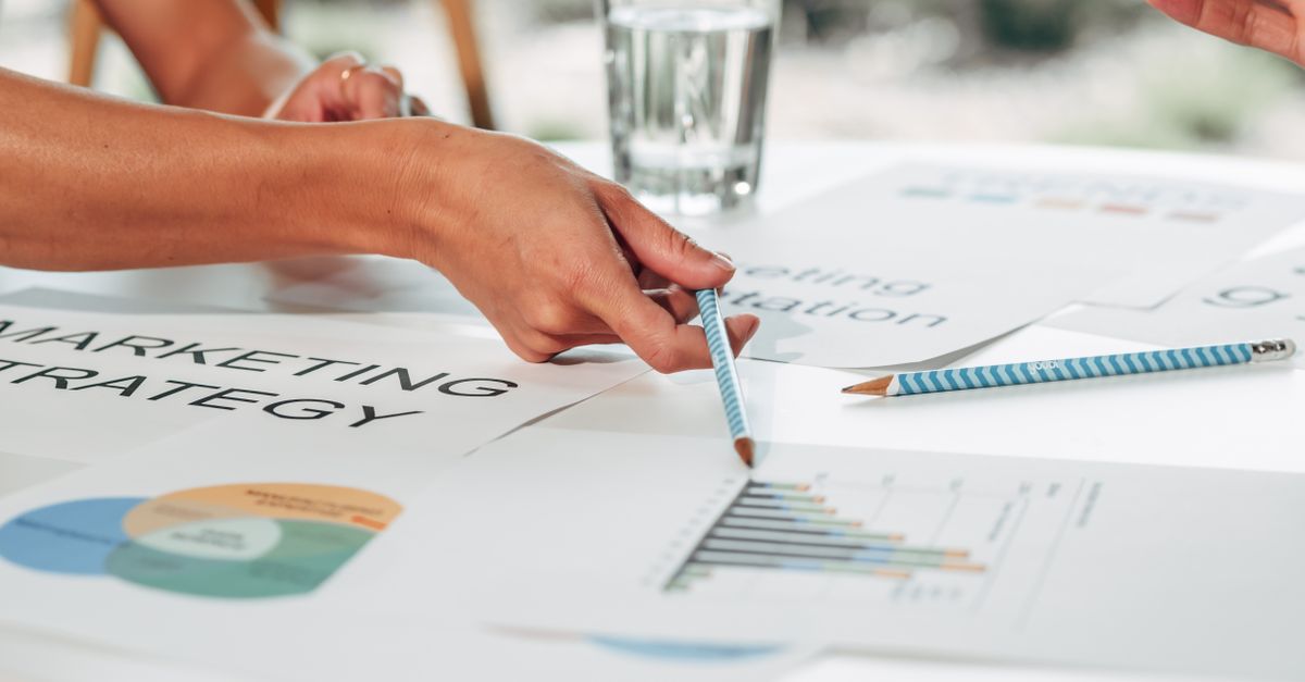 Hands discussing marketing strategy with charts in an office setting.