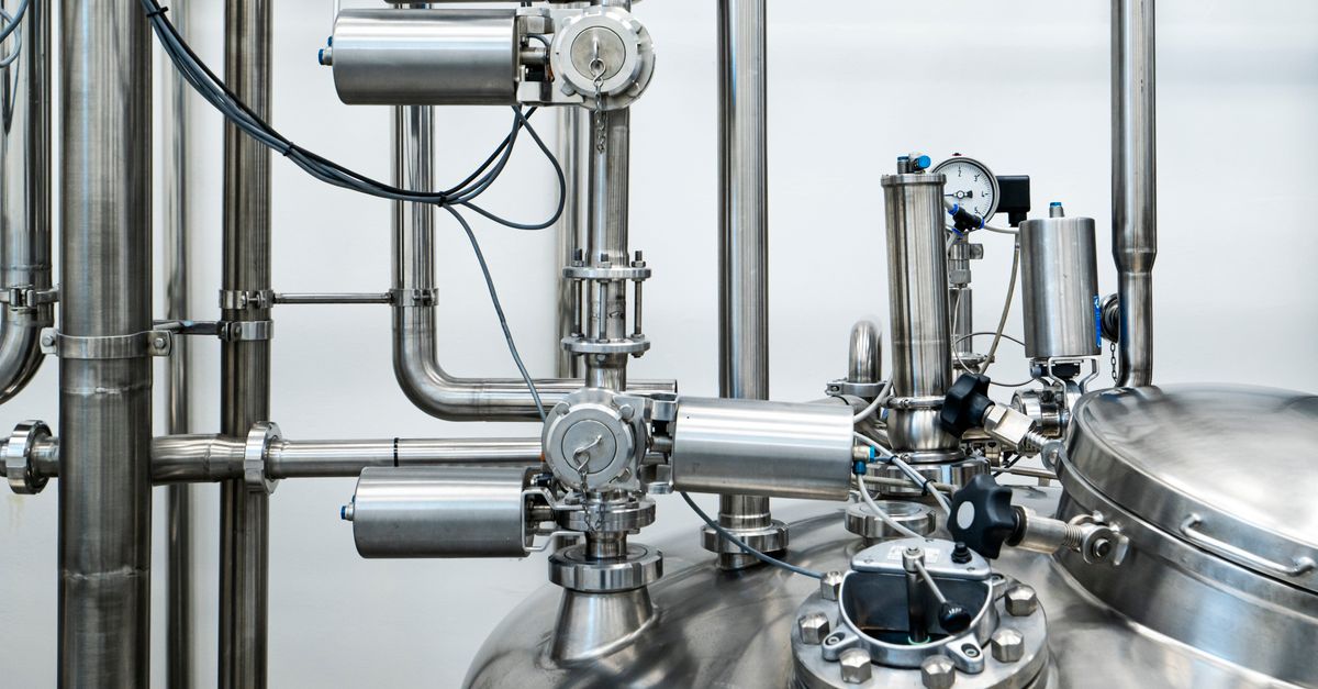 Close-up of stainless steel machinery and pipes in an industrial setting, showcasing modern engineering.