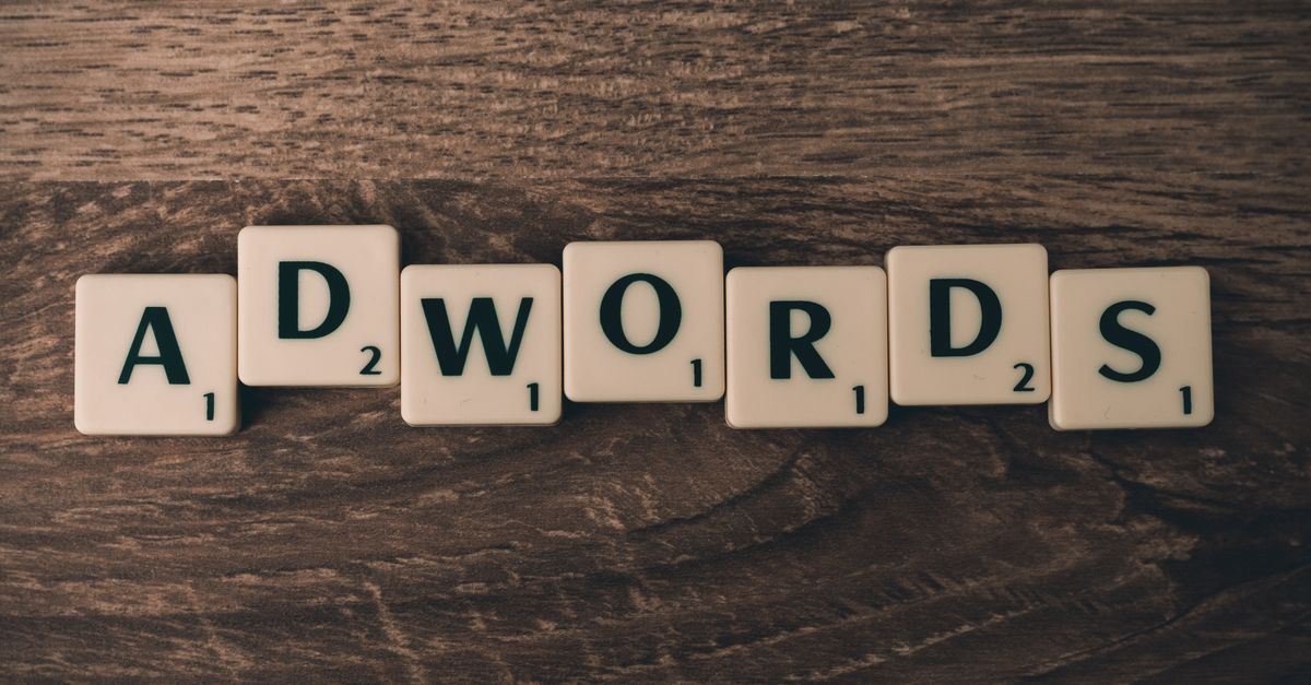 Scrabble tiles spelling 'AdWords' on a wooden surface, symbolizing digital marketing concepts.
