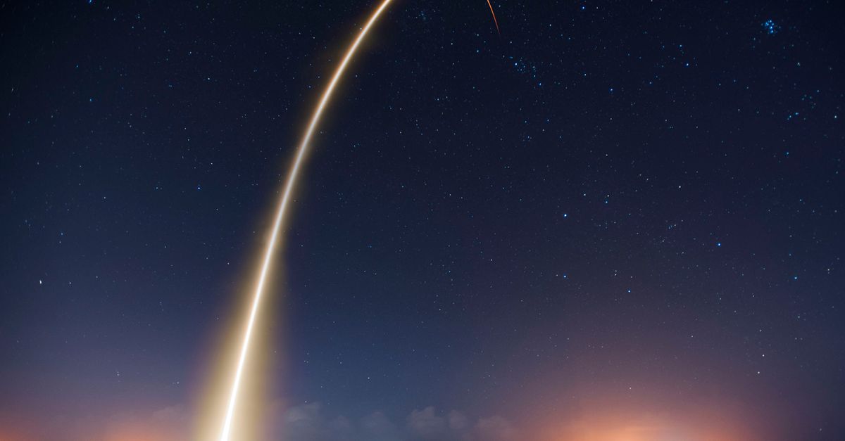 Spectacular long exposure of a rocket launch under a clear, starry night sky showcasing the trail.