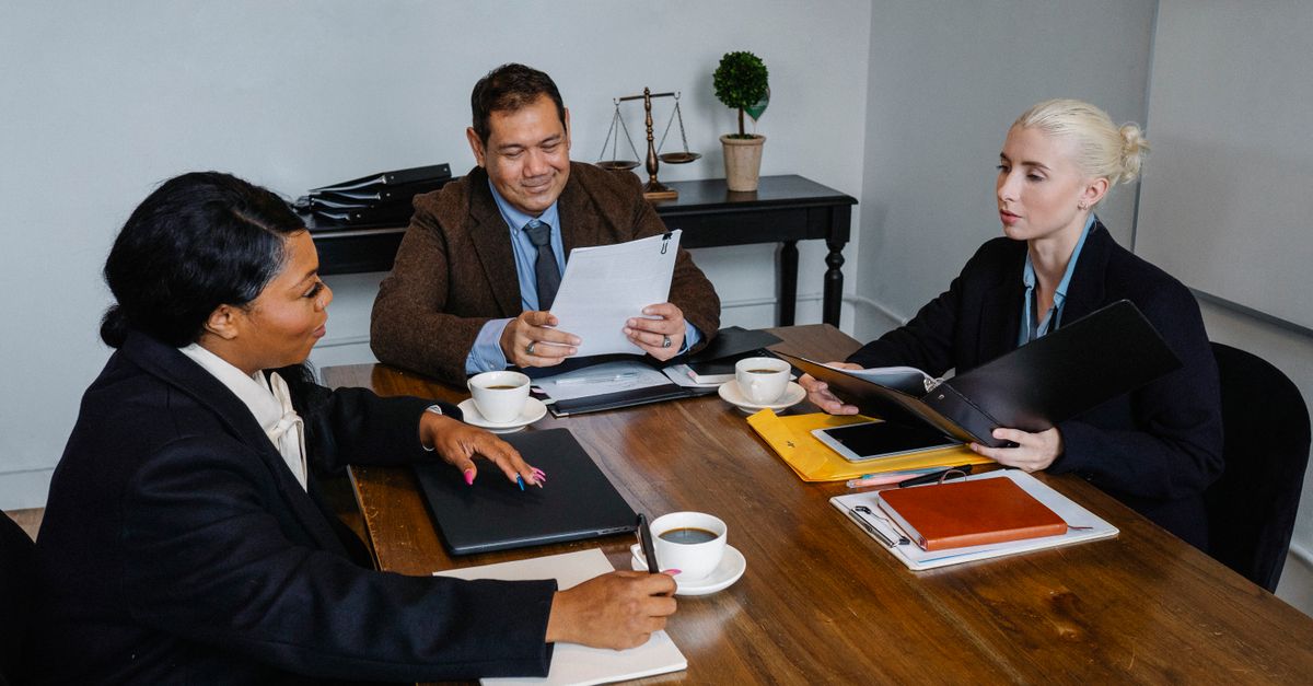 Group of diverse coworkers in formal suits discussing business issues during meeting in office