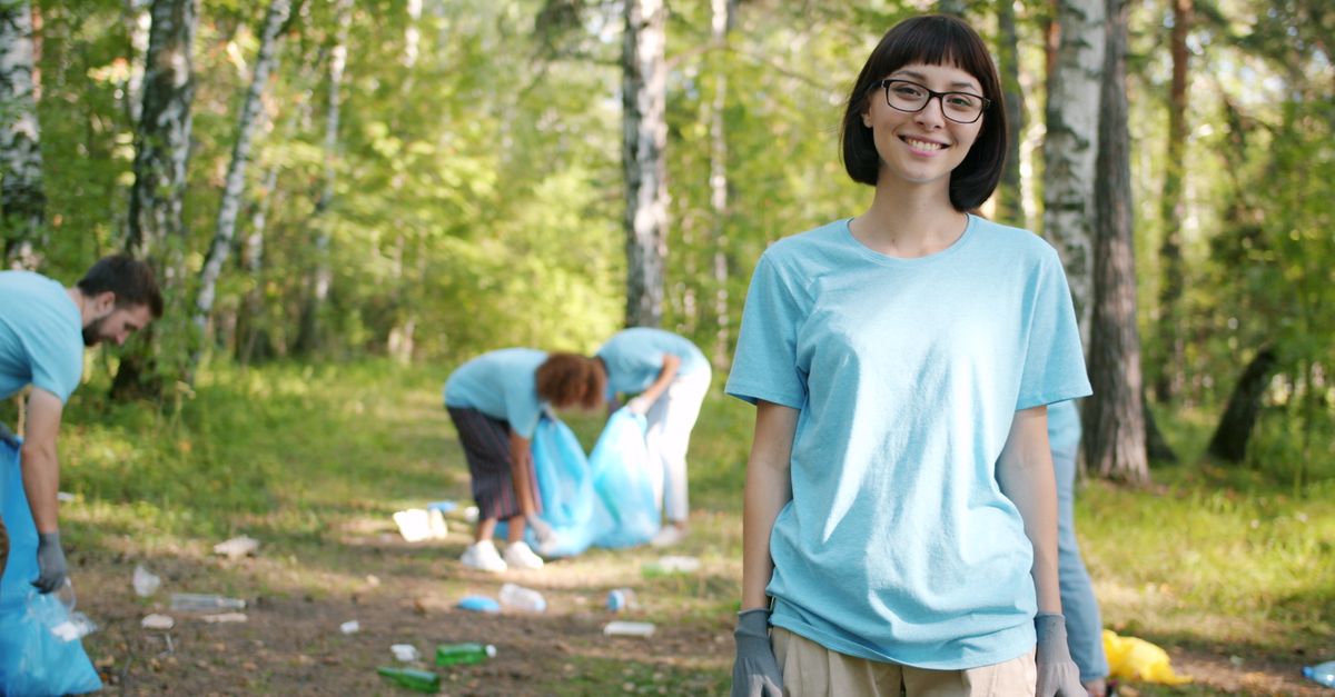 Group of volunteers collecting litter in a forest, focusing on environmental conservation.