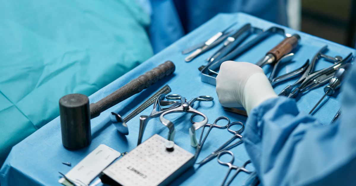 Close-up of surgical tools and surgeon's hands in an operating room setup.
