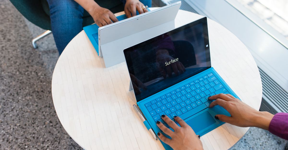 Two individuals working on laptops indoors, embodying remote work and technology.