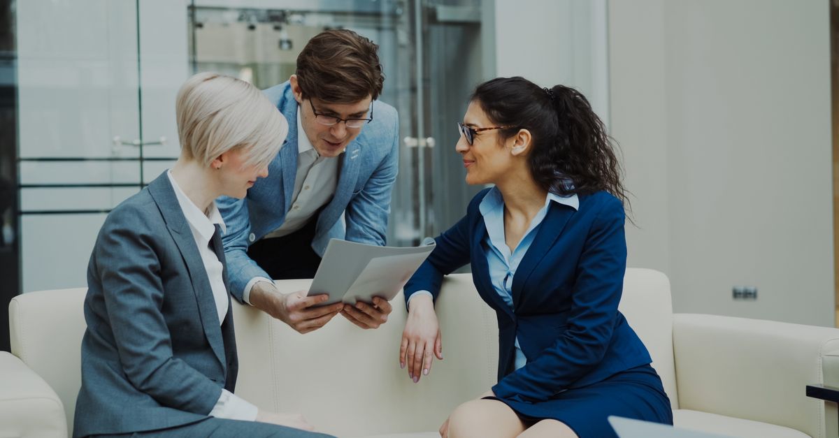 Three business professionals engaged in a meeting, collaborating over a tablet.