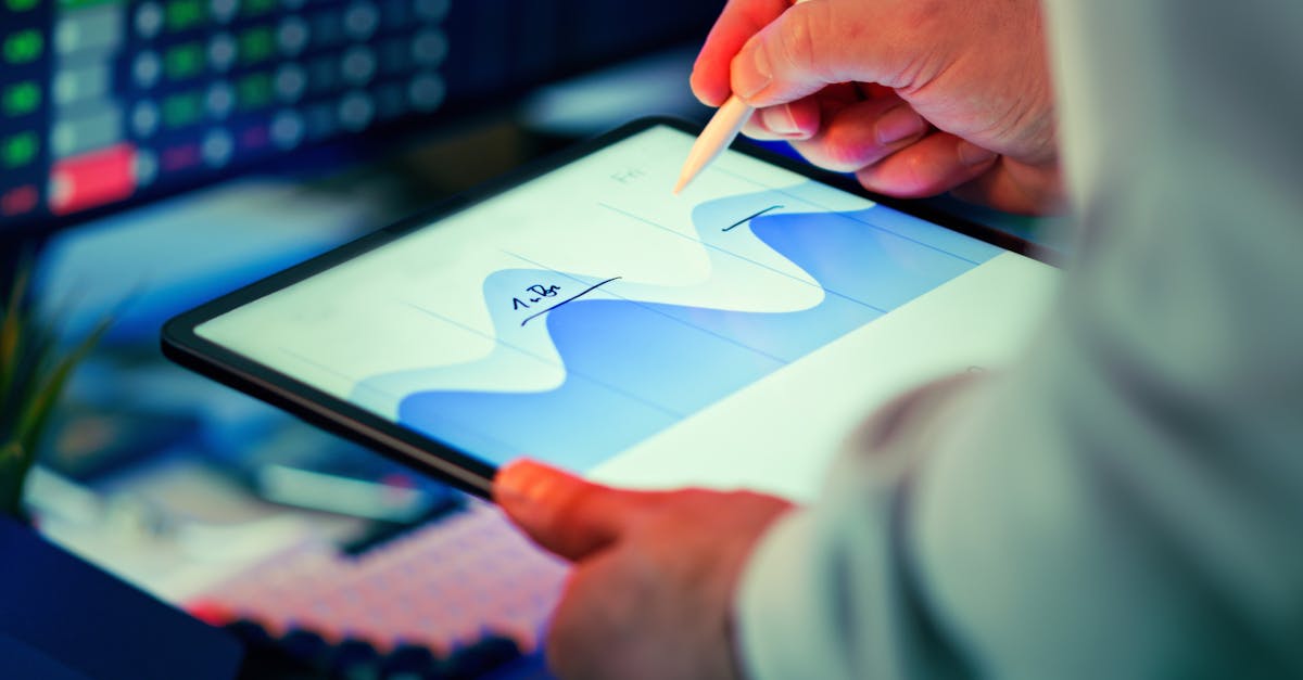 Professional analyzing data chart on a tablet with stylus in an office setting.
