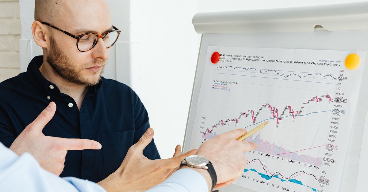 Business professionals discussing financial graphs on a flipchart during a daylight meeting.