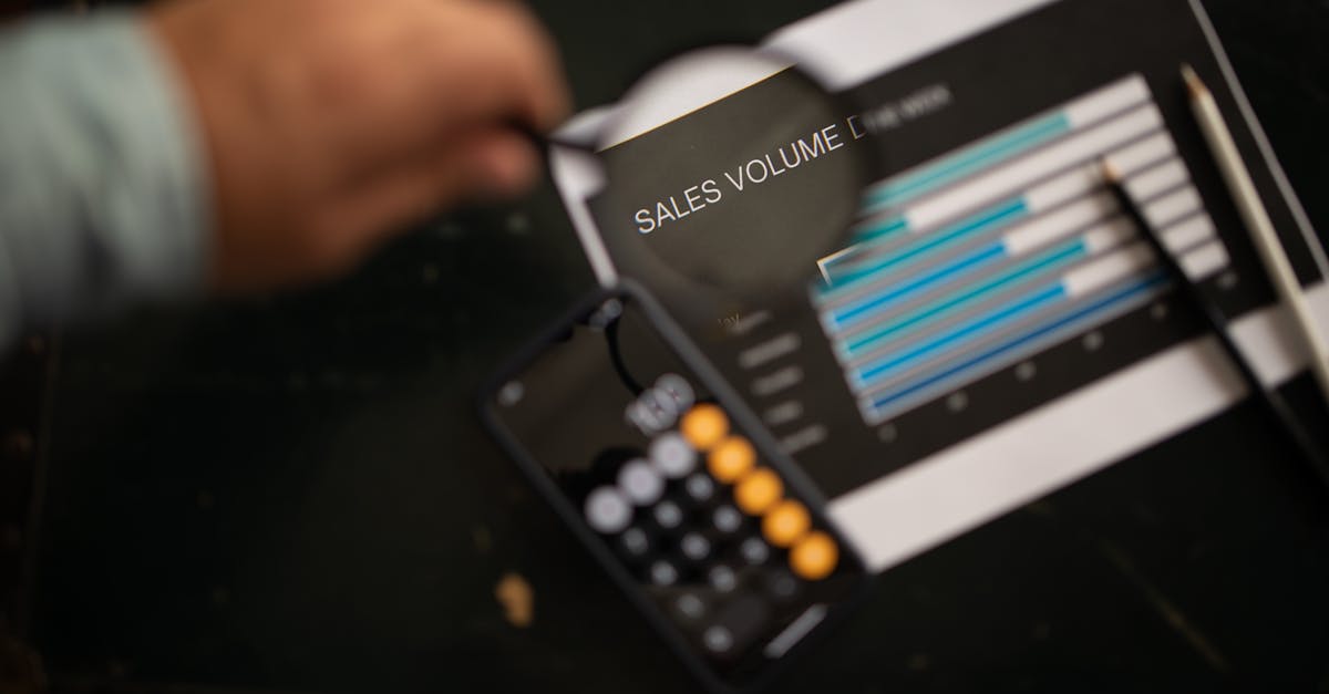 A focused examination of sales volume data using a magnifying glass and calculator.