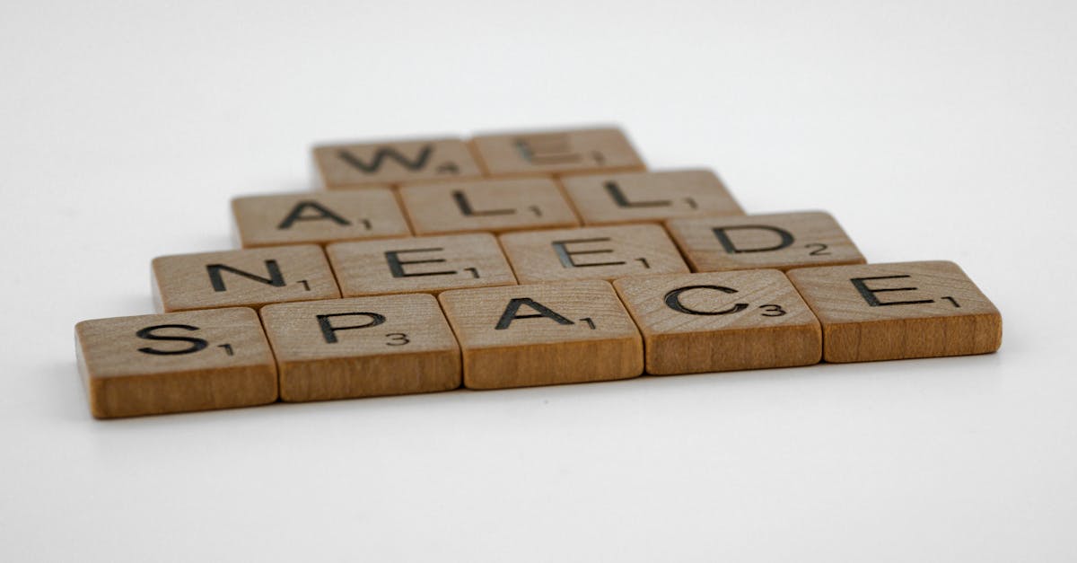 Scrabble tiles forming the phrase 'We All Need Space' arranged on a white surface.