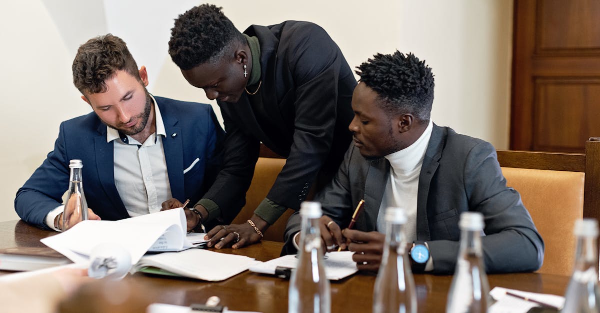 Three professionals working together at a table, discussing documents in an office setting.