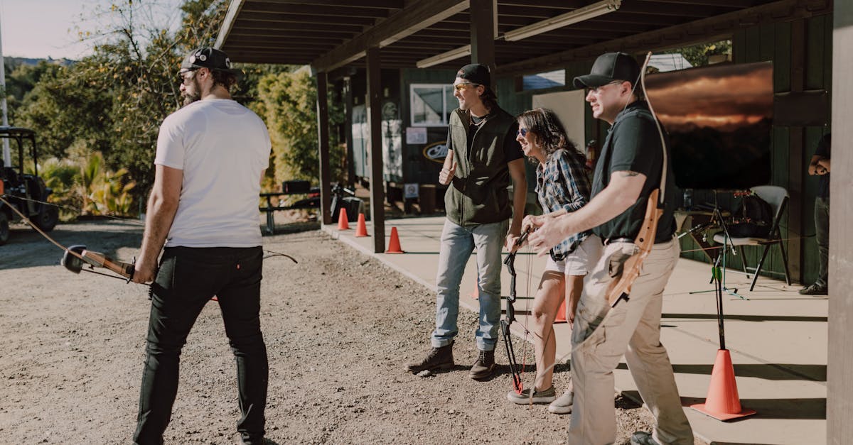 A group of adults practicing archery outdoors under a sunny day.