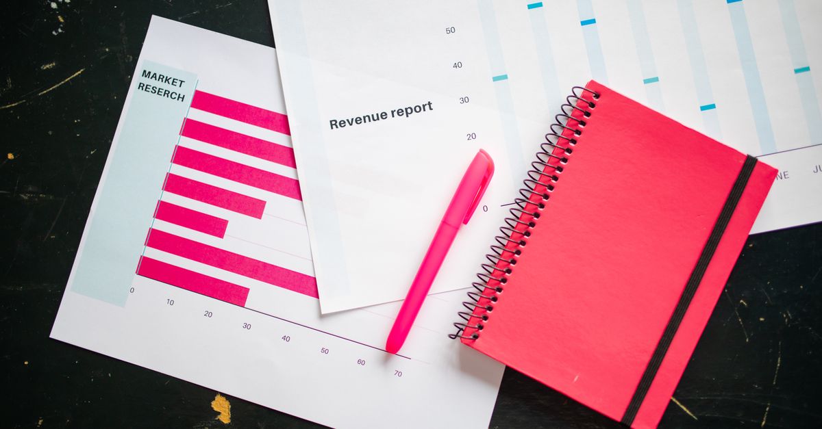 Overhead shot of a desk with charts, a red notebook, and a pen for business analysis.