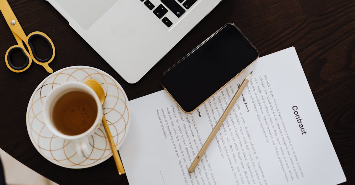 Top-view of a workspace with contract, coffee, laptop, and smartphone focused on business productivity.