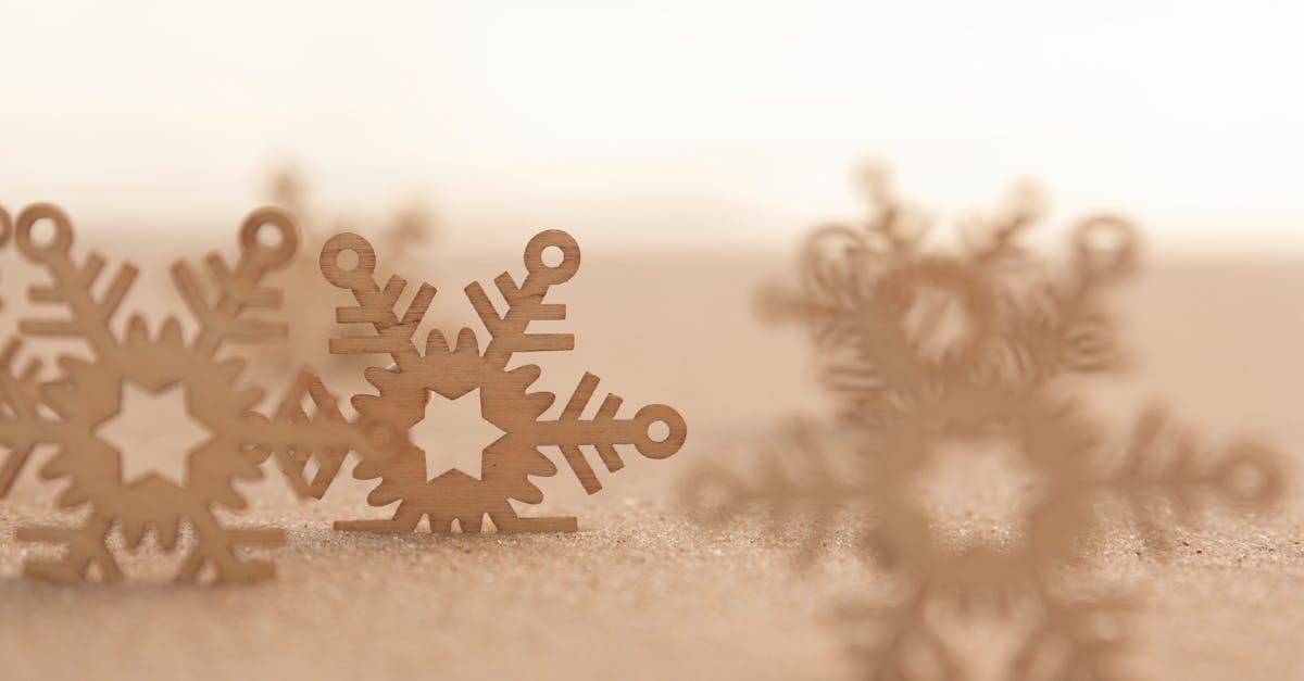 Wooden snowflake decorations on sand, evoking winter holiday themes.