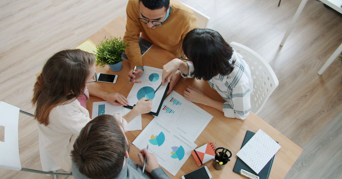 Group of professionals reviewing business charts around a table.
