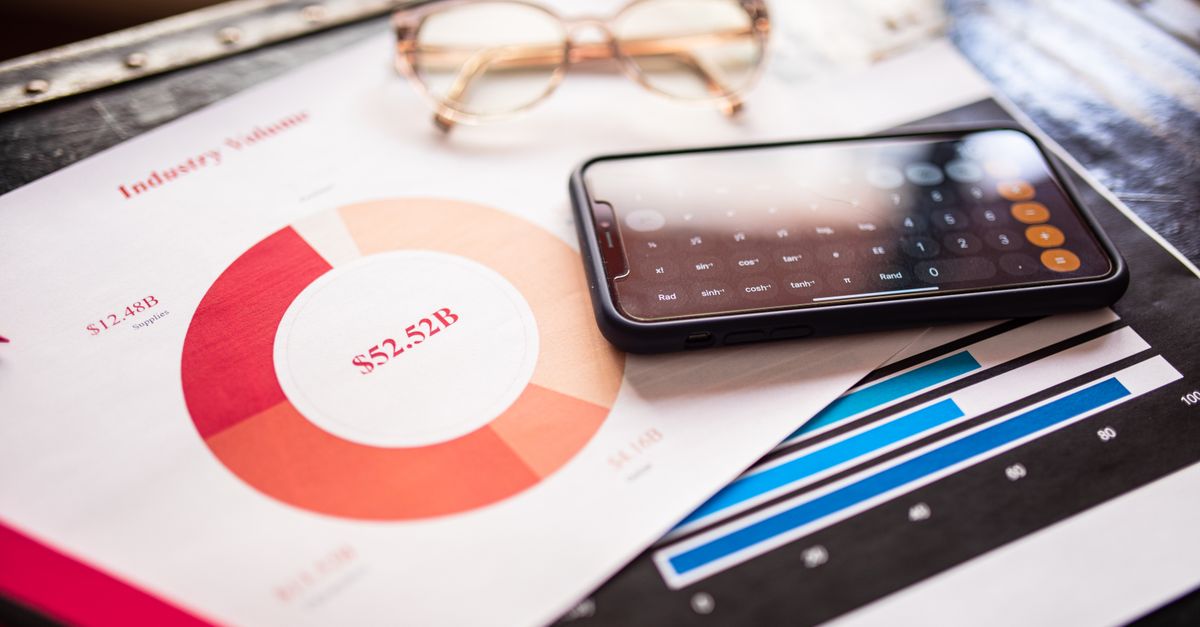 Smartphone on business documents with charts and graphs, illustrating financial analysis.
