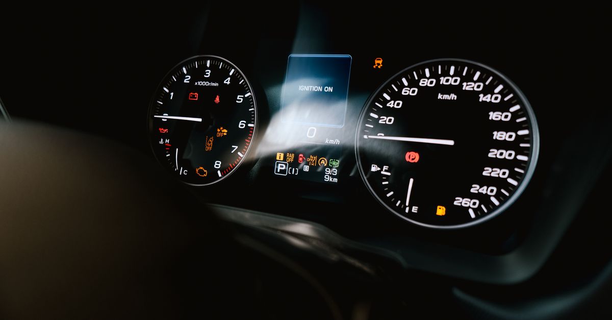 Detailed view of a car dashboard showing speedometer, tachometer, and warning lights, with ignition on.