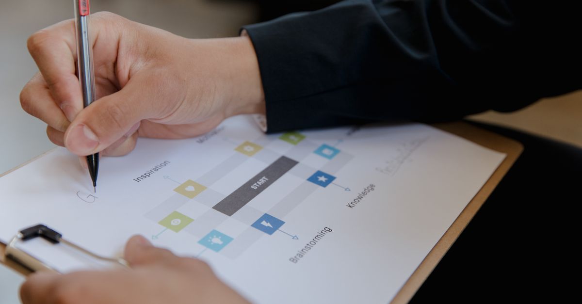 Close-up of a person writing on a business strategy document with a pen.