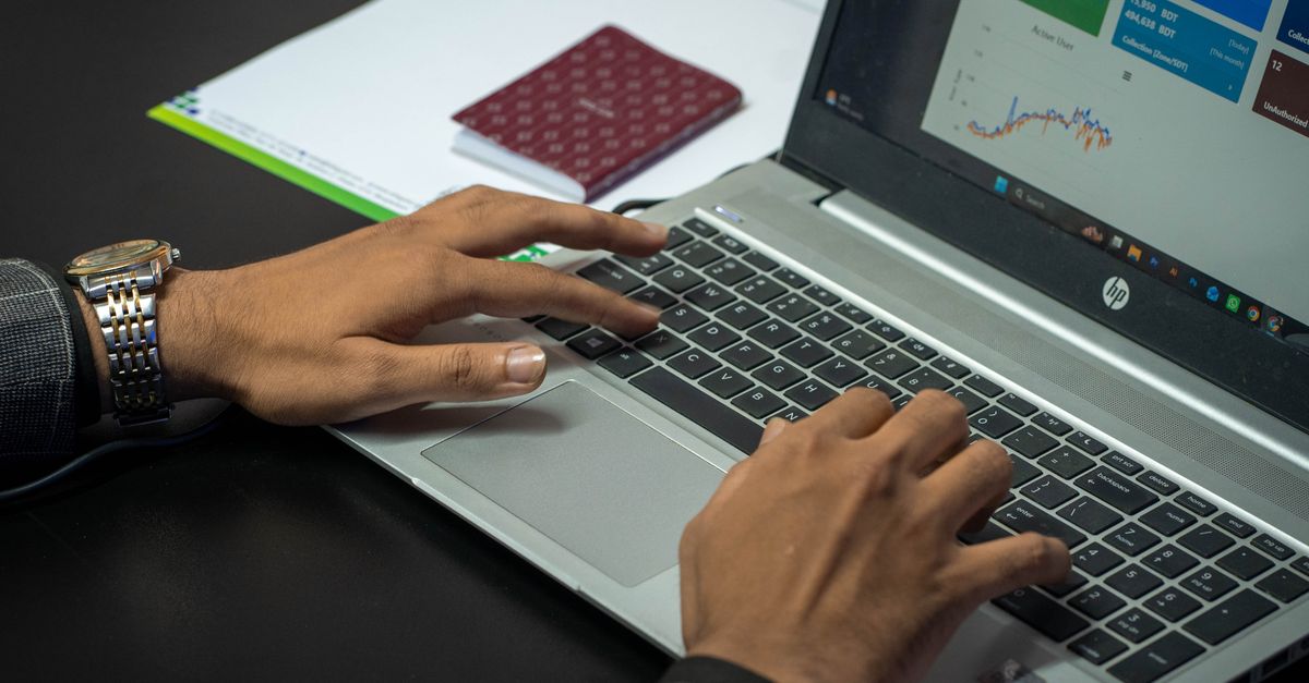 Close-up of hands on a laptop keyboard with a business dashboard on screen, ideal for finance or tech themes.